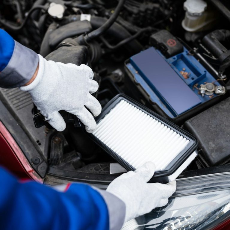 Mechaniker tauscht den Luftfilter in einem Auto aus. Mechaniker tauscht den Luftfilter in einem Auto aus.