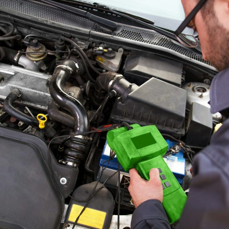 Prüfung Mechaniker prüft Autokomponenten mit einem grünen Diagnosetool.